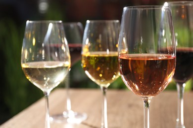 Different tasty wines in glasses on wooden table