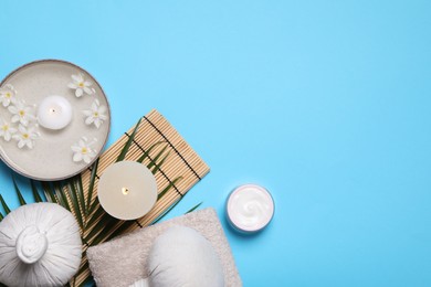 Flat lay composition with spa products, burning candle and beautiful flowers on light blue background. Space for text