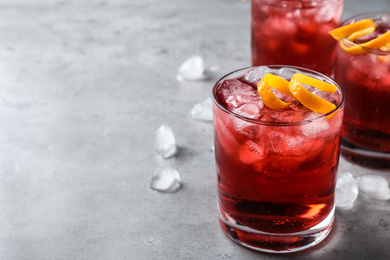 Photo of Fresh Negroni cocktail with orange zest on grey table. Space for text