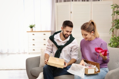 Young couple opening parcels on sofa in living room