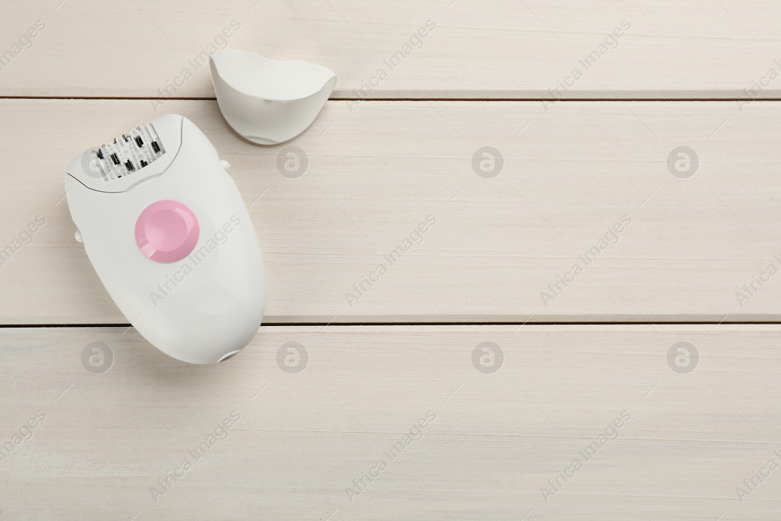 Photo of Modern epilator and cap on white wooden table, flat lay. Space for text