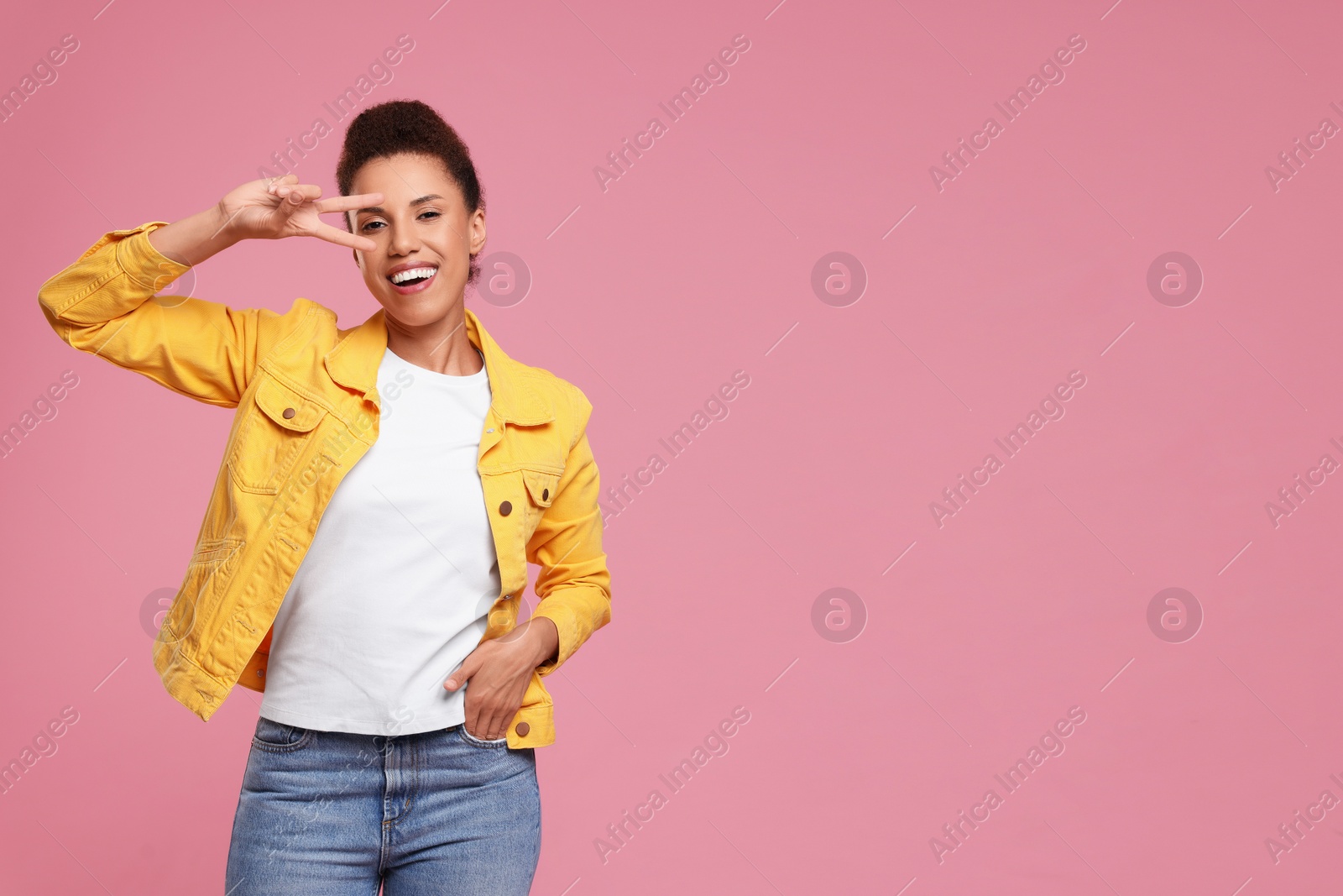 Photo of Happy young woman dancing on pink background. Space for text
