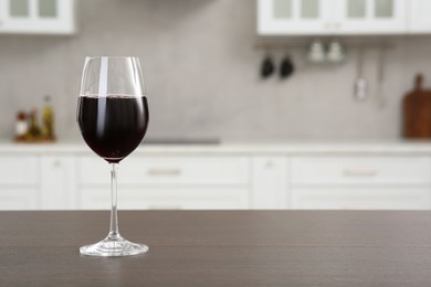 Photo of Glass of red wine on countertop in kitchen, space for text