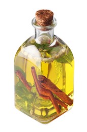 Photo of Glass bottle of cooking oil with spices and herbs isolated on white