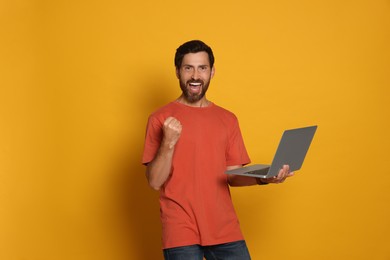 Happy man with laptop on orange background