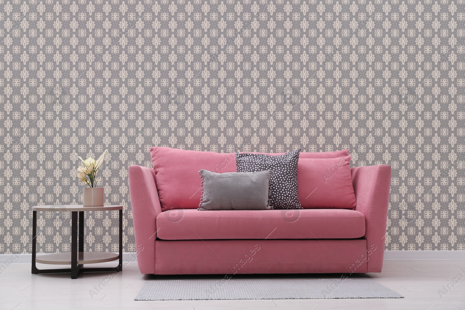 Image of Comfortable pink sofa and side table near wall. Minimalist living room interior