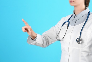 Photo of Female doctor pointing on color background, closeup