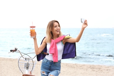 Attractive woman taking selfie near bicycle on sea coast