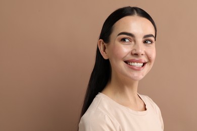 Beautiful woman with clean teeth smiling on beige background, space for text