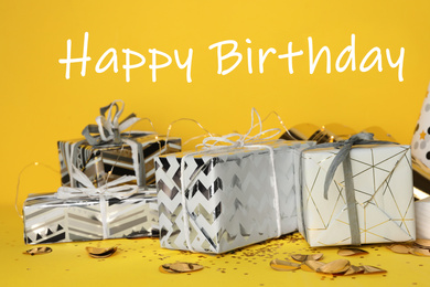 Photo of Gift boxes and text Happy Birthday on yellow background