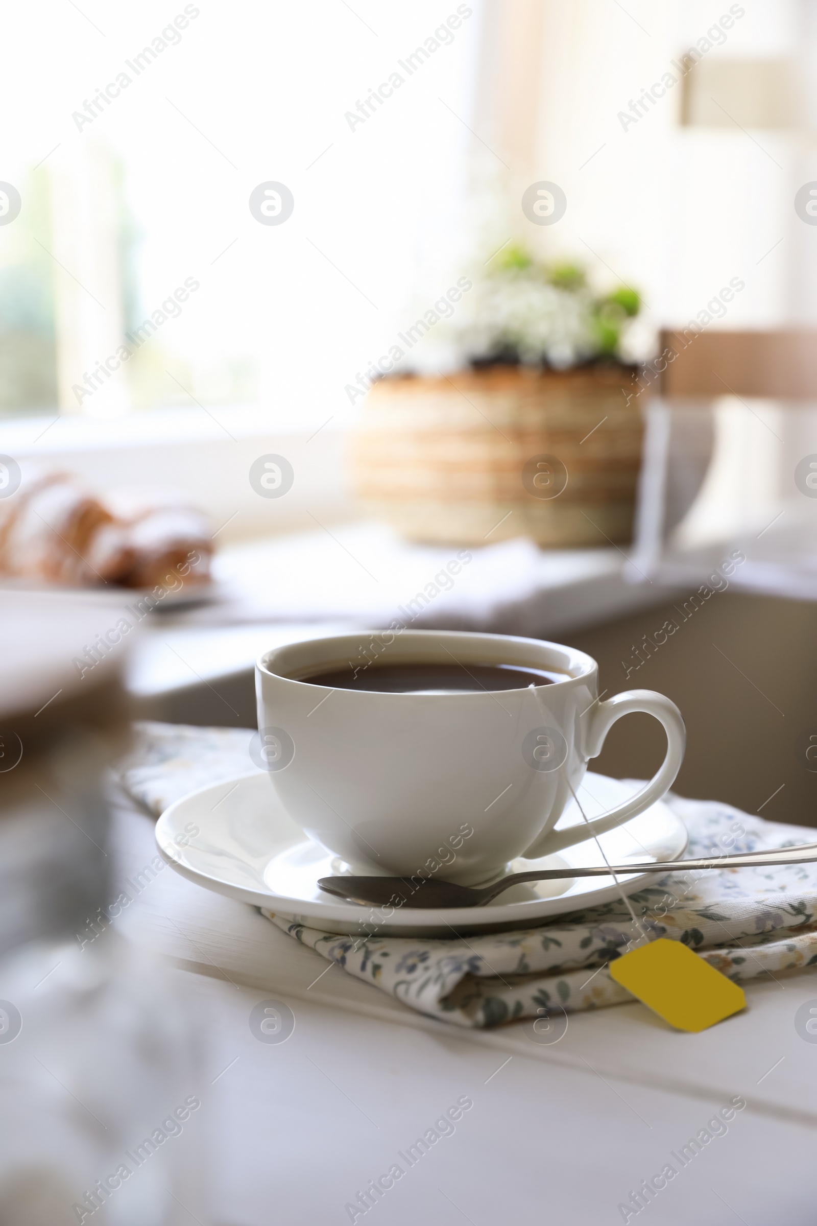 Photo of Tea bag in cup on white wooden table indoors