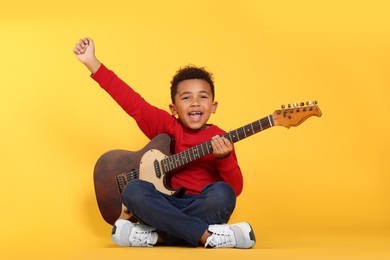 African-American boy with electric guitar on yellow background