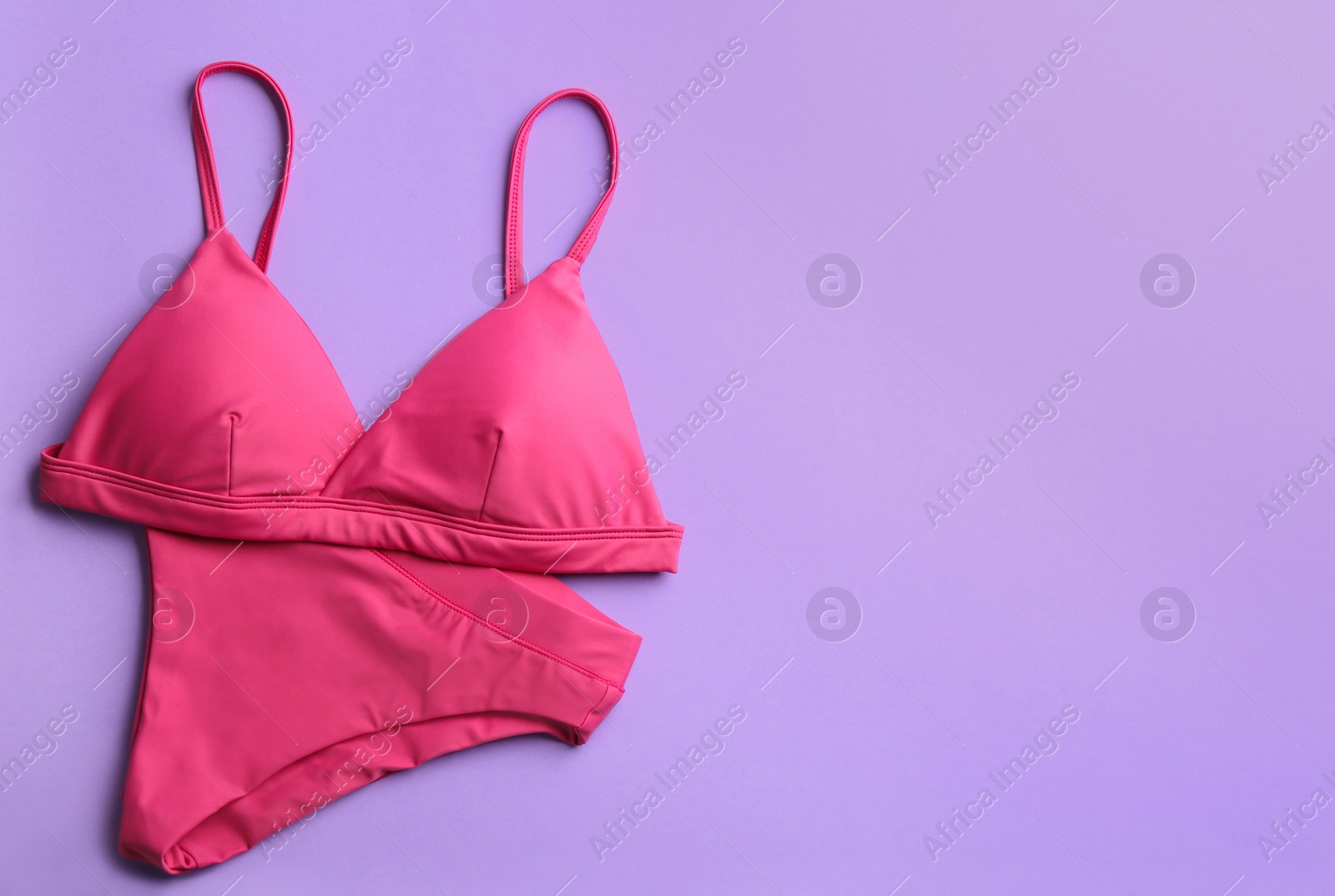 Photo of Beautiful pink bikini on lilac background, top view. Space for text