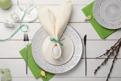 Festive table setting with painted egg, plates and willow twigs, flat lay. Easter celebration