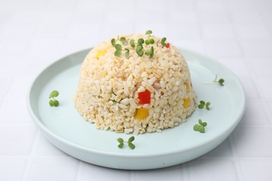 Delicious bulgur with vegetables and microgreens on white table, closeup