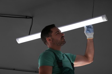 Photo of Ceiling light. Electrician installing led linear lamp indoors