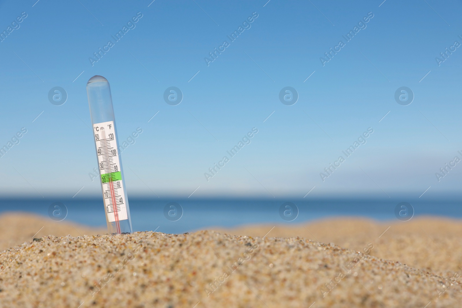 Photo of Weather thermometer in sand near sea, space for text