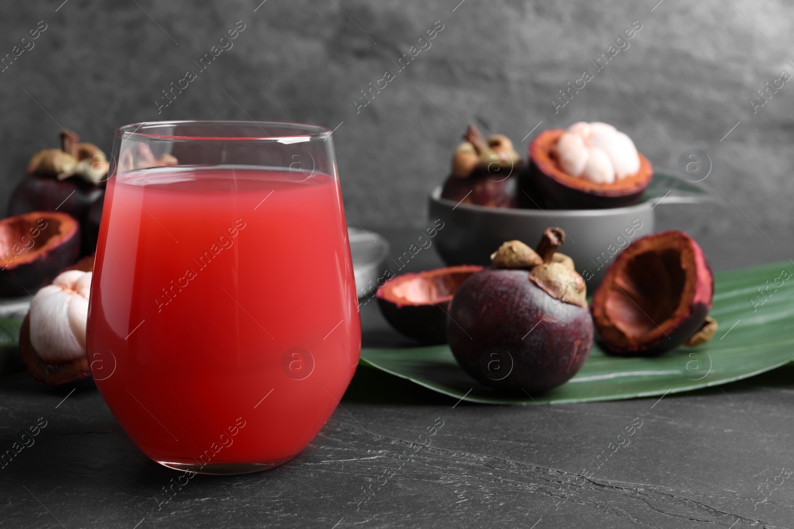 Photo of Delicious mangosteen juice and fresh fruits on dark table, space for text