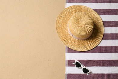 Photo of Straw hat, sunglasses, towel and space for text on beach sand, top view. Summer vacation