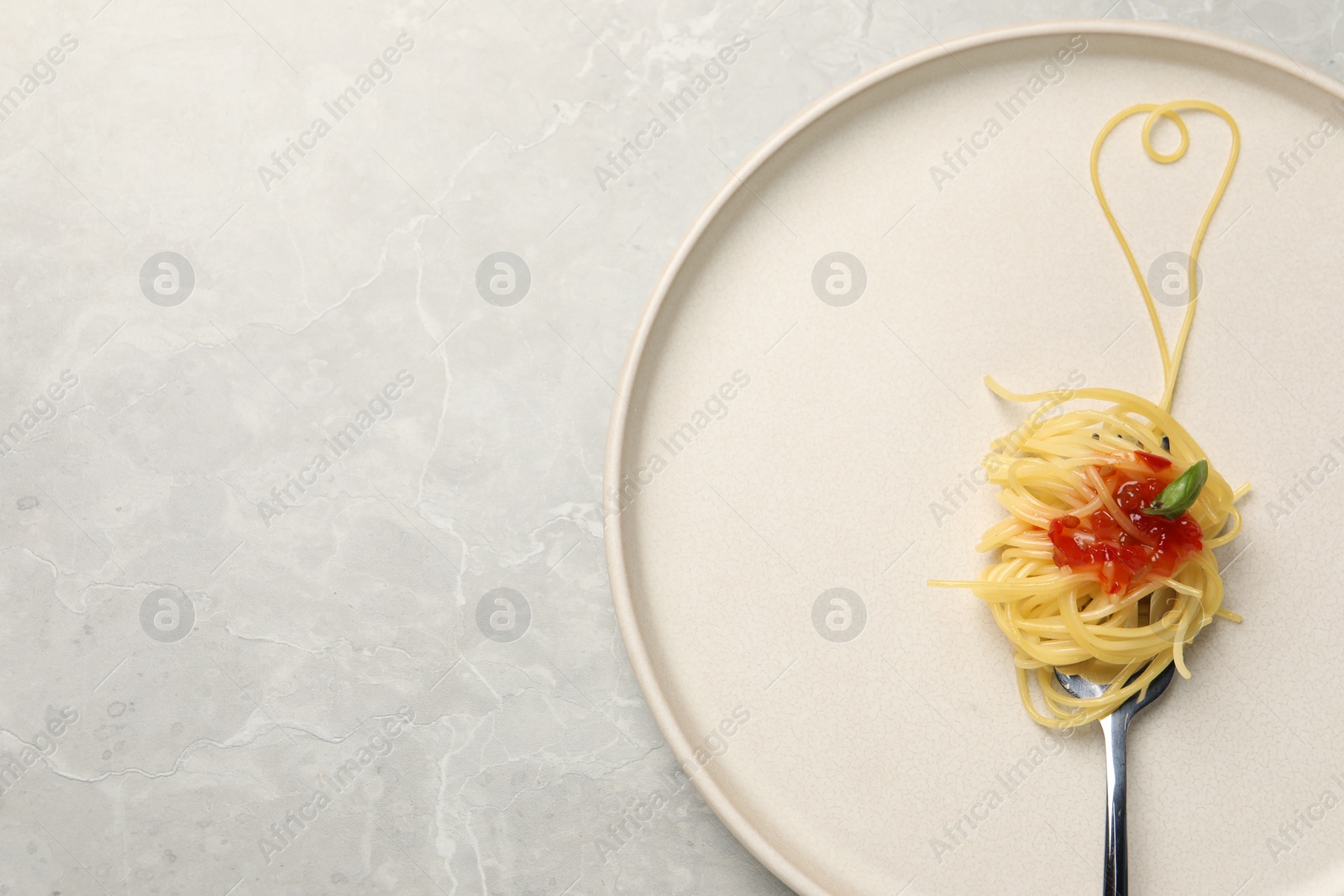 Photo of Heart made with spaghetti and fork on grey table, top view. Space for text