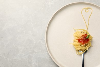 Photo of Heart made with spaghetti and fork on grey table, top view. Space for text