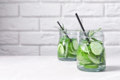 Photo of Natural lemonade with cucumber and rosemary in jars on table