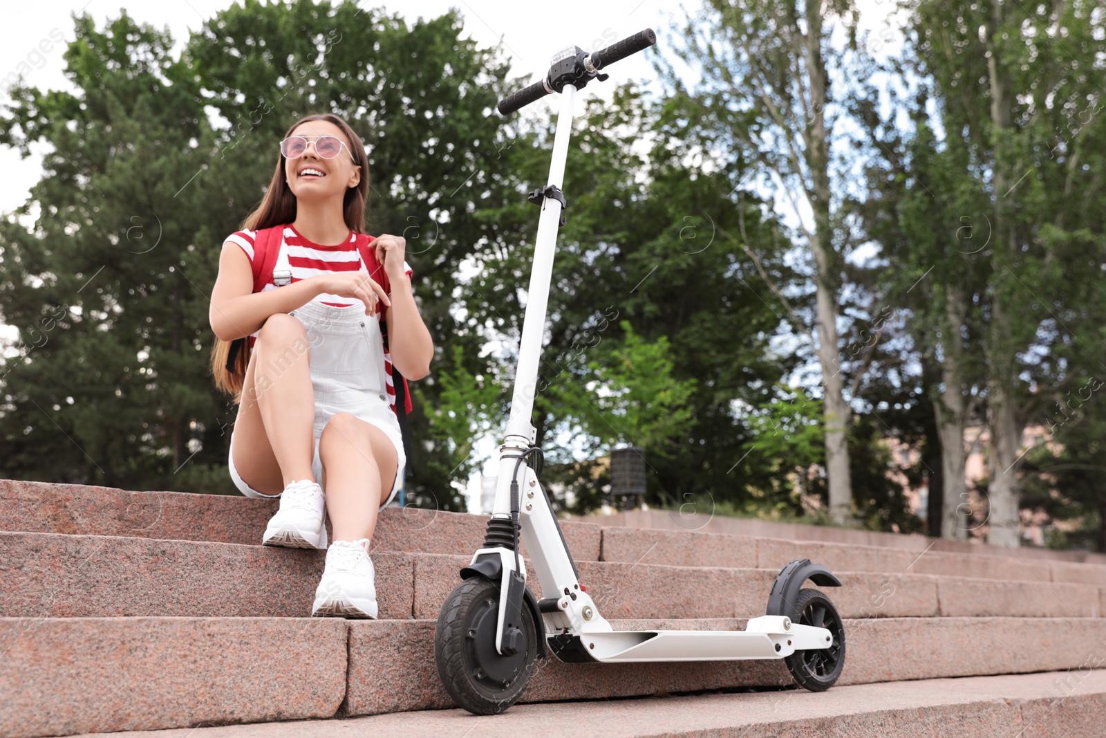 Photo of Young woman with electric kick scooter on stairs outdoors