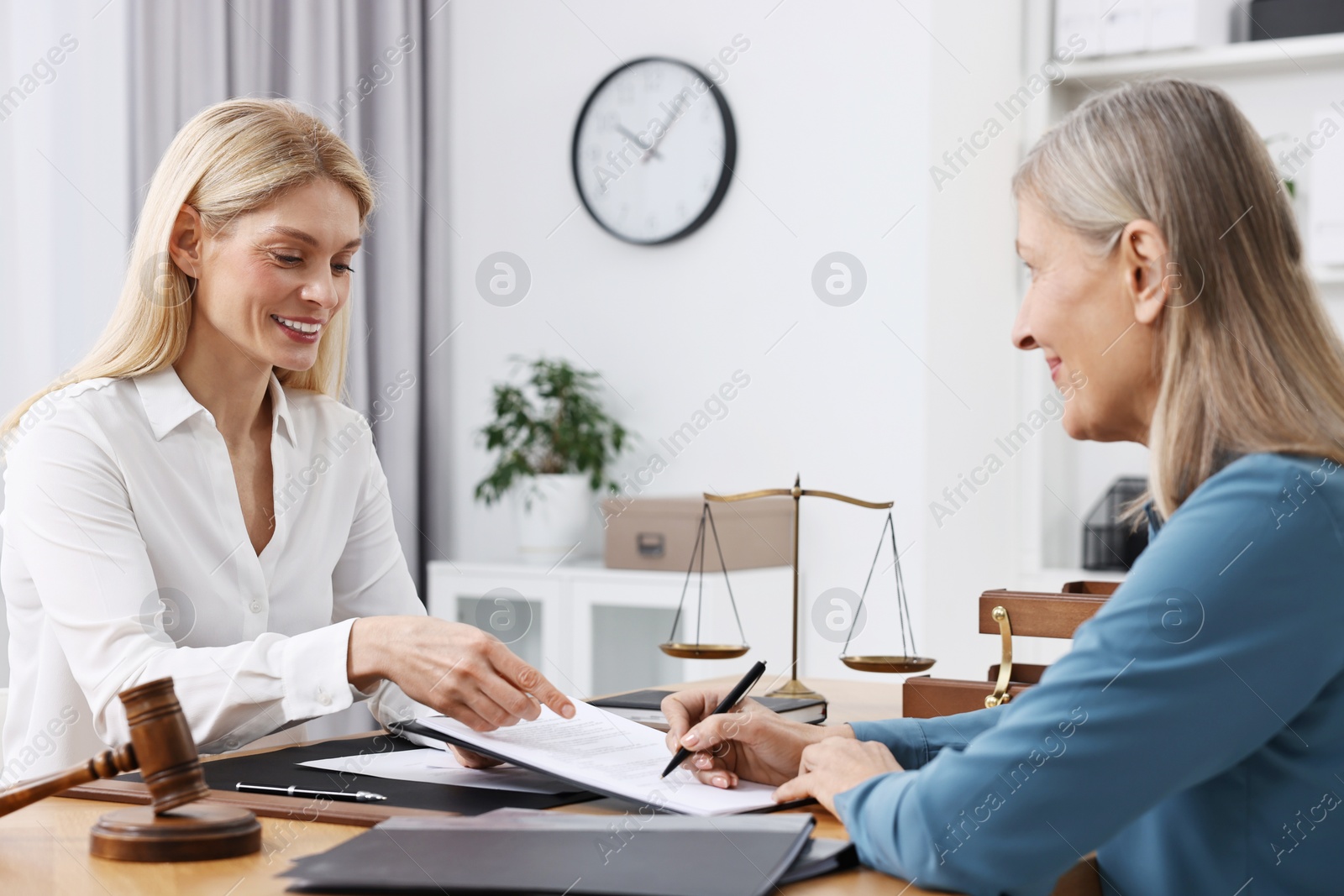 Photo of Senior woman signing document in lawyer's office