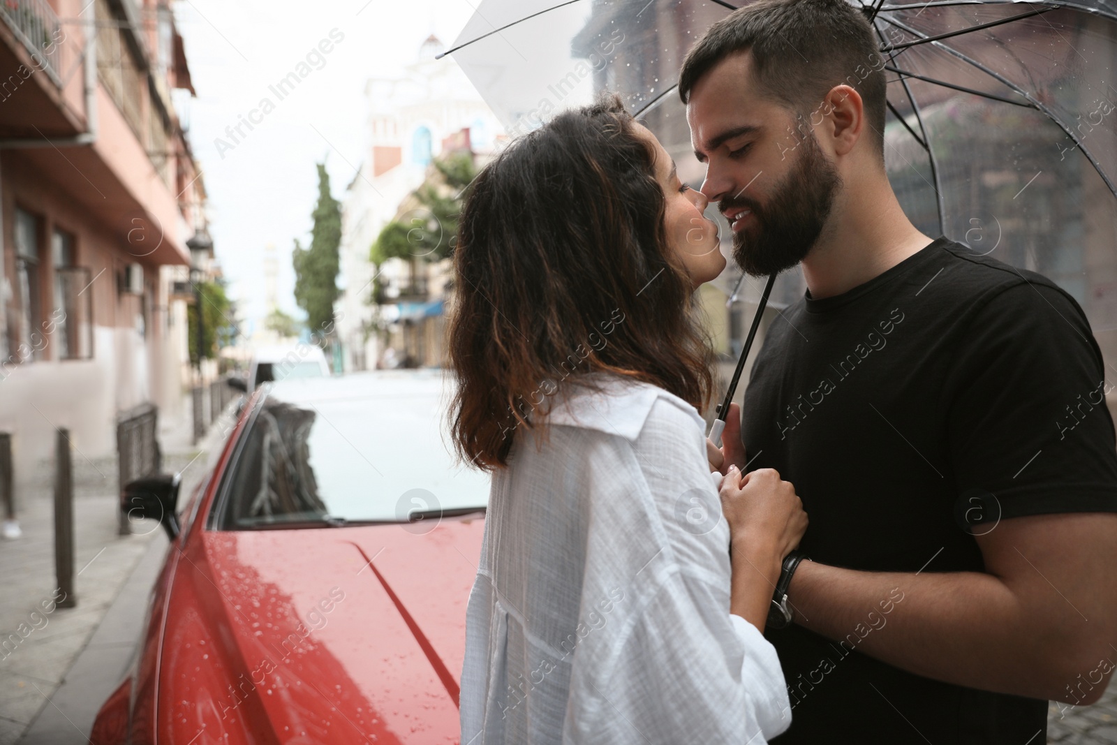 Photo of Young couple with umbrella enjoying time together under rain on city street, space for text