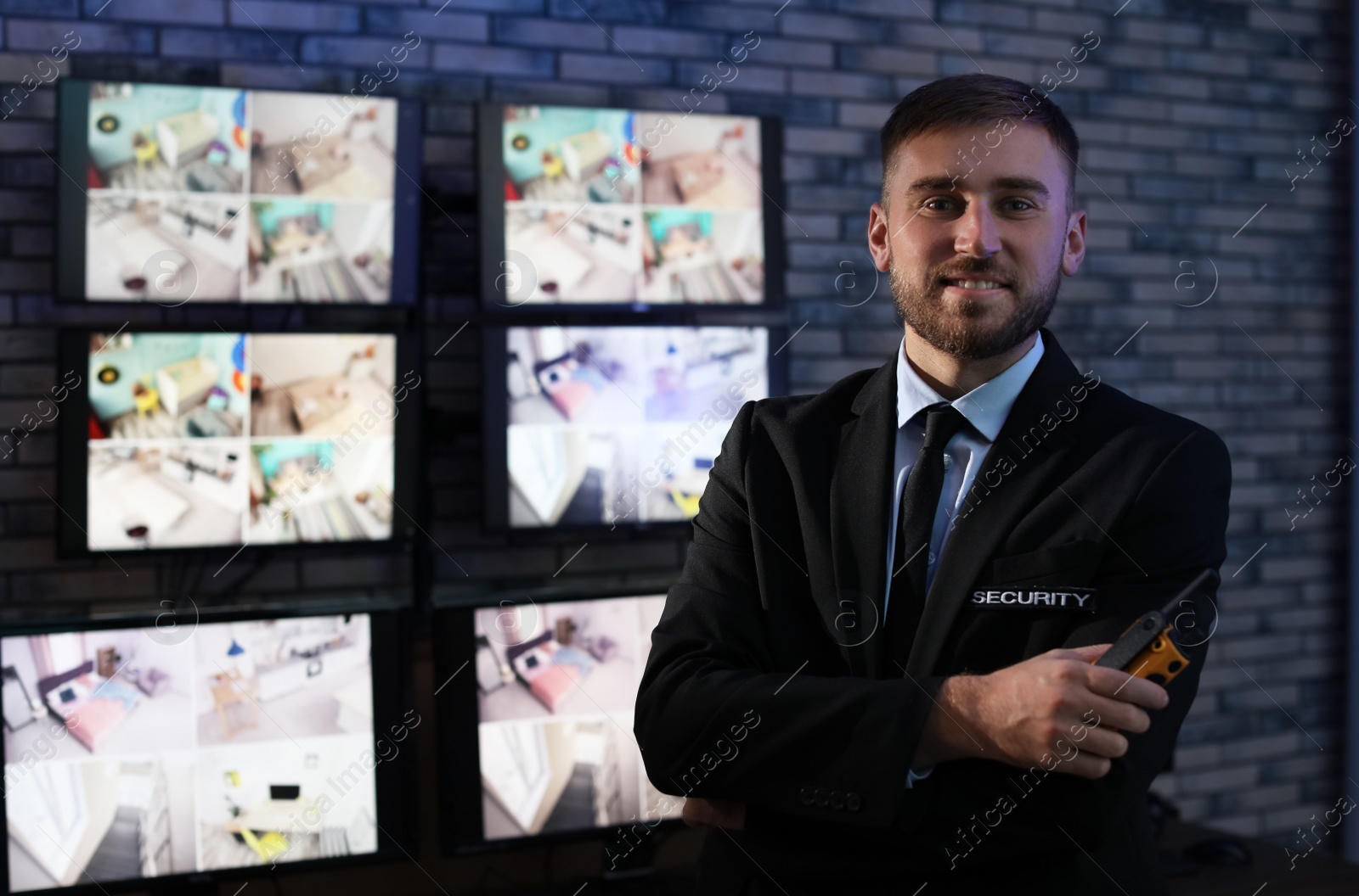 Photo of Male security guard with portable transmitter near cameras indoors