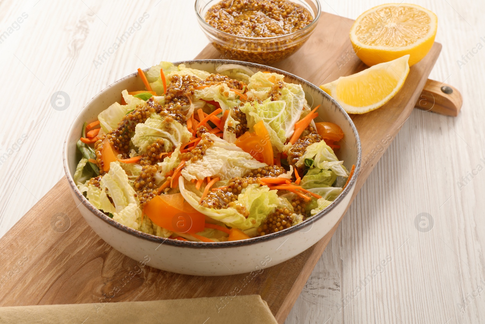 Photo of Delicious salad with Chinese cabbage and mustard seed dressing on white wooden table