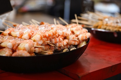 Delicious shrimp skewers served in dish on table, closeup