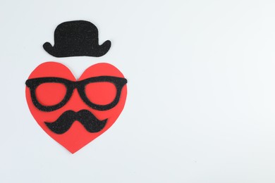 Man's face made of paper heart, fake mustache, glasses and hat on light background, top view. Space for text
