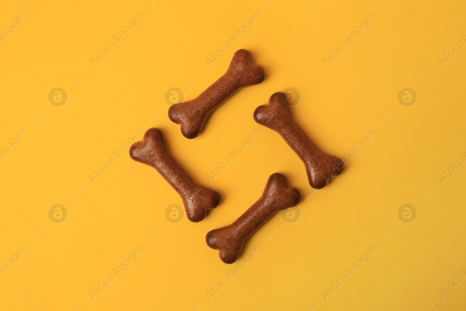 Photo of Bone shaped dog cookies on orange background, flat lay
