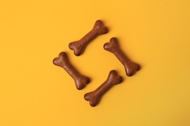 Photo of Bone shaped dog cookies on orange background, flat lay