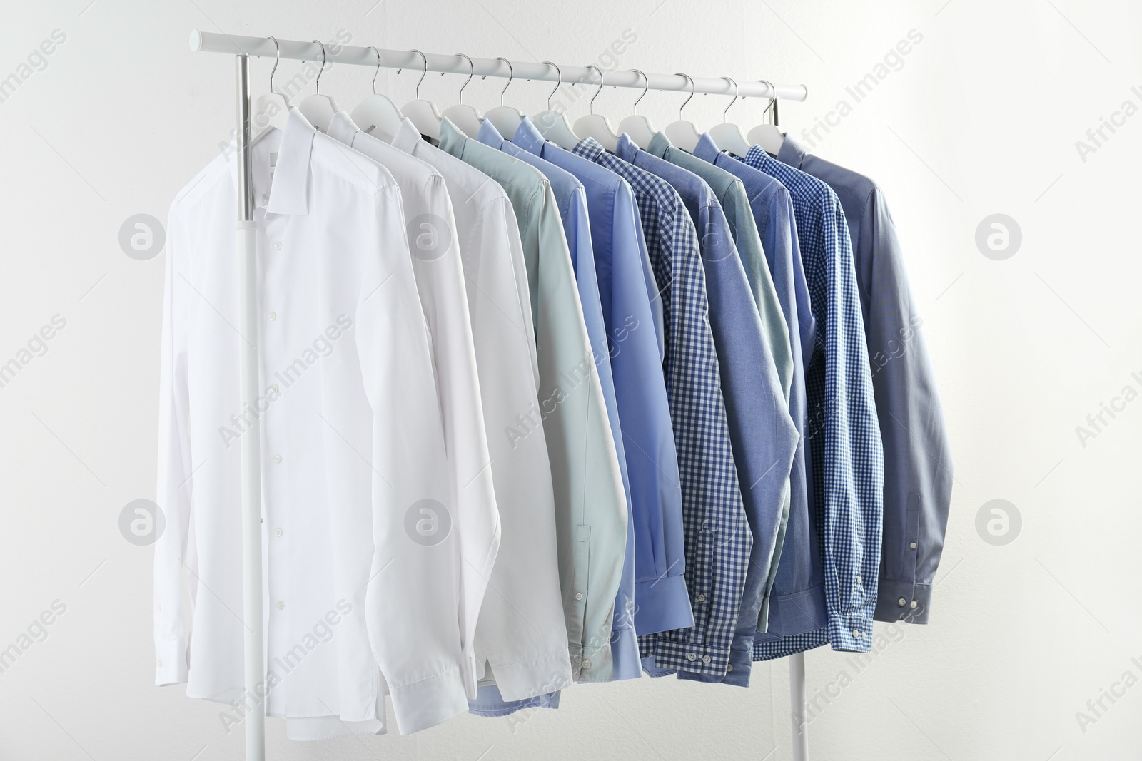 Photo of Men's clothes hanging on wardrobe rack against white background