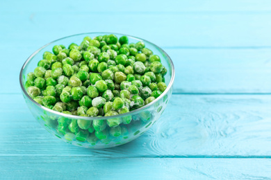 Photo of Frozen green peas on light blue wooden table, closeup. Vegetable preservation