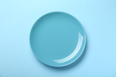 Empty ceramic plate on light blue background, top view