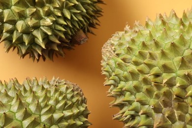 Photo of Fresh ripe durians on orange background, closeup