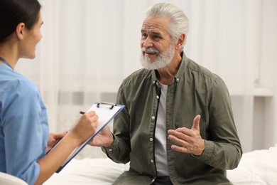 Photo of Smiling elderly patient talking with nurse in hospital