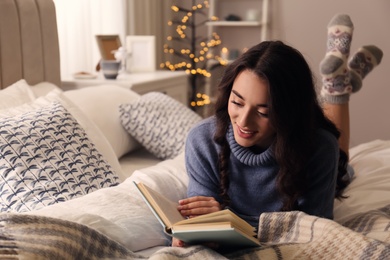 Photo of Young woman reading book at home. Winter atmosphere