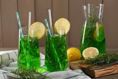 Photo of Jug and glasses of refreshing tarragon drink with lemon slices on table