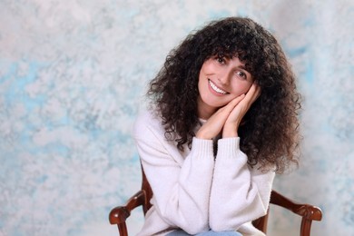 Photo of Portrait of happy young woman on chair against color background. Space for text