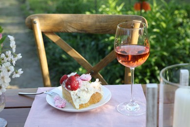 Photo of Glass of wine and cake on table served for romantic date in garden