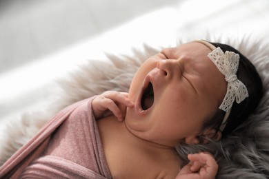 Photo of Cute newborn baby yawning on fuzzy blanket, closeup