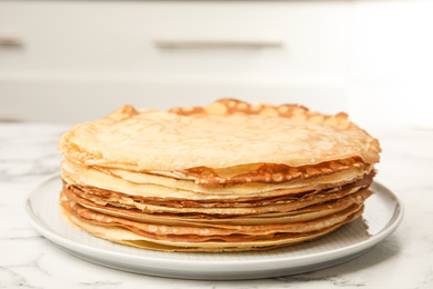 Stack of fresh thin pancakes on white marble table
