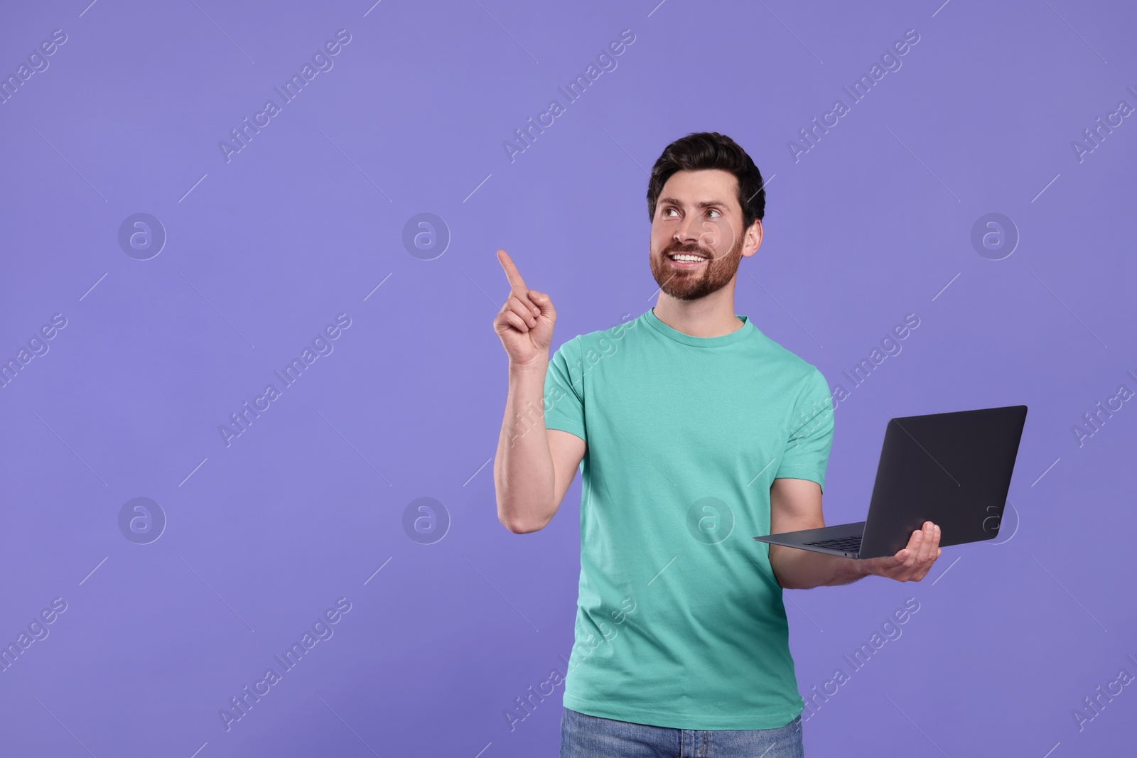 Photo of Happy man with laptop on purple background. Space for text