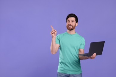 Happy man with laptop on purple background. Space for text