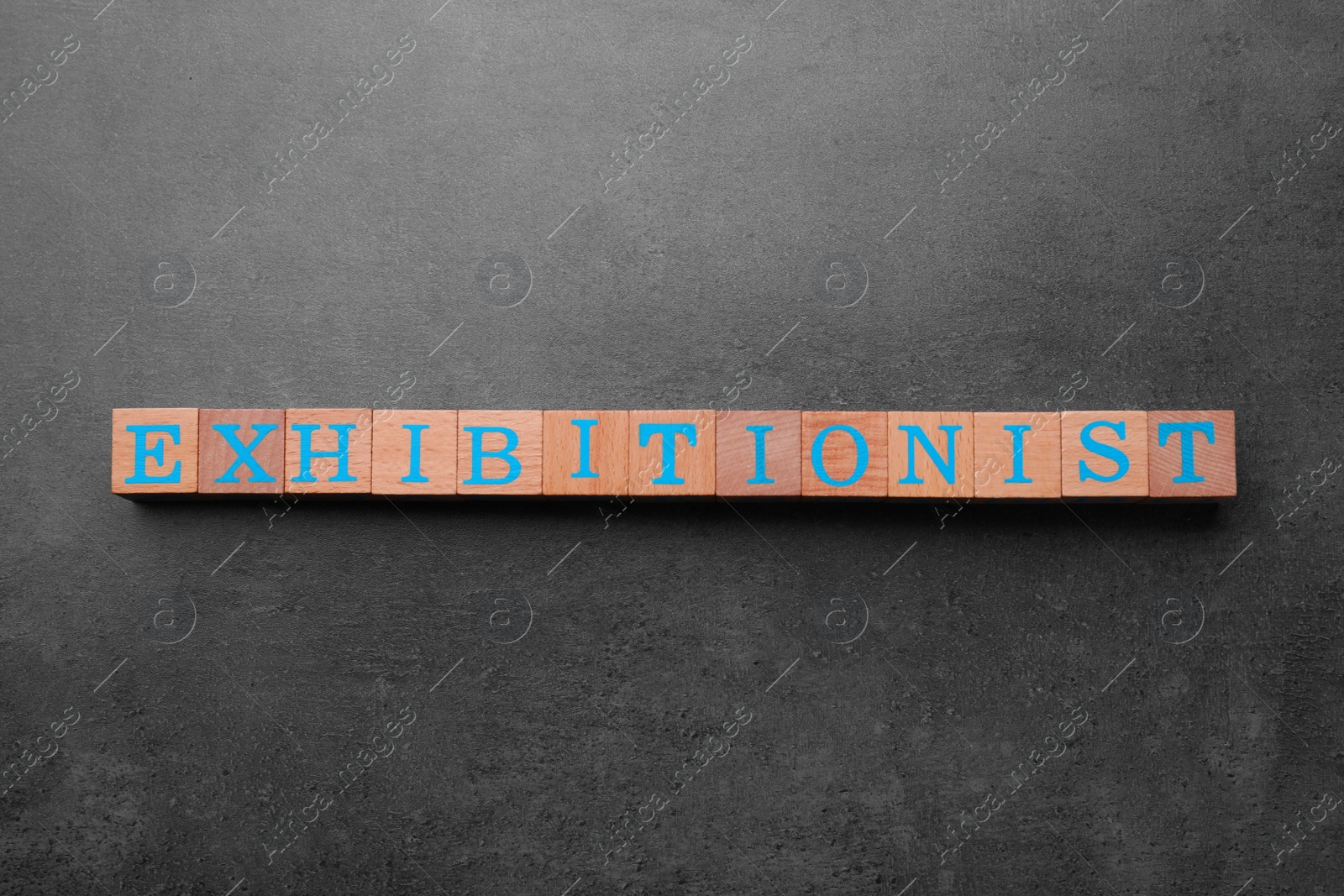 Photo of Word EXHIBITIONIST made with wooden cubes on grey table, flat lay