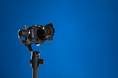 Modern professional video camera on blue background. Space for text